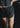 Person wearing black athletic shorts with a brand logo on a dark background